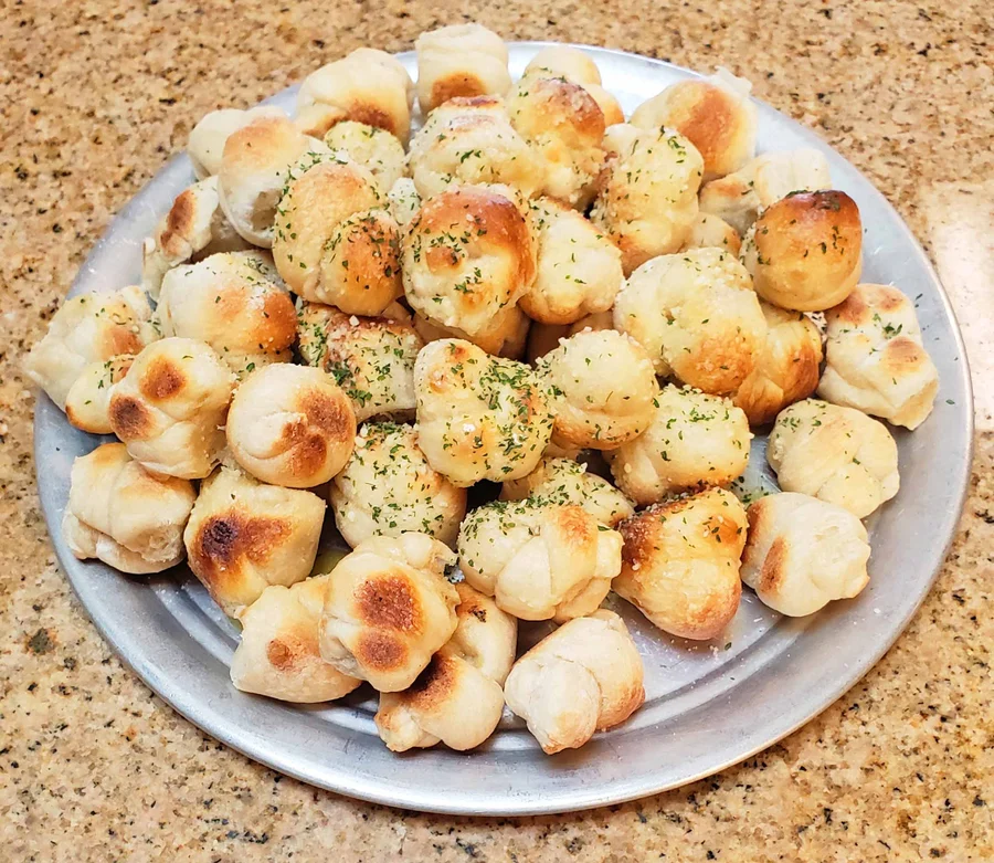 Plate of garlic knots topped with parmesan and parsley
